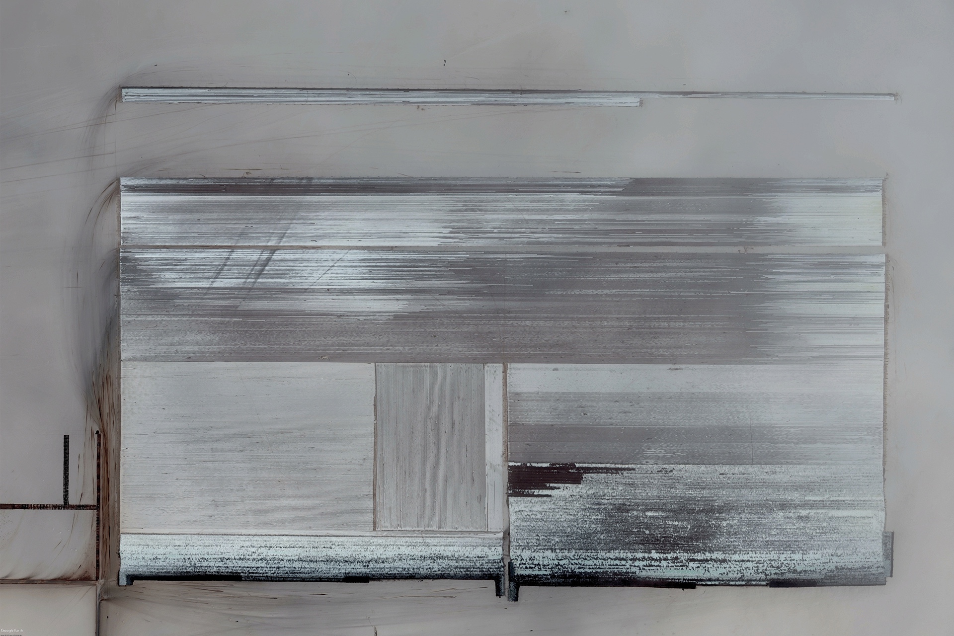 A satellite image collected by the artist of a dried out solar evaporation pond. The water that concentrates the salt minerals has completely evaporated, and the salt mostly harvested. What remains, and what is seen in the photo are thousands of thin lines