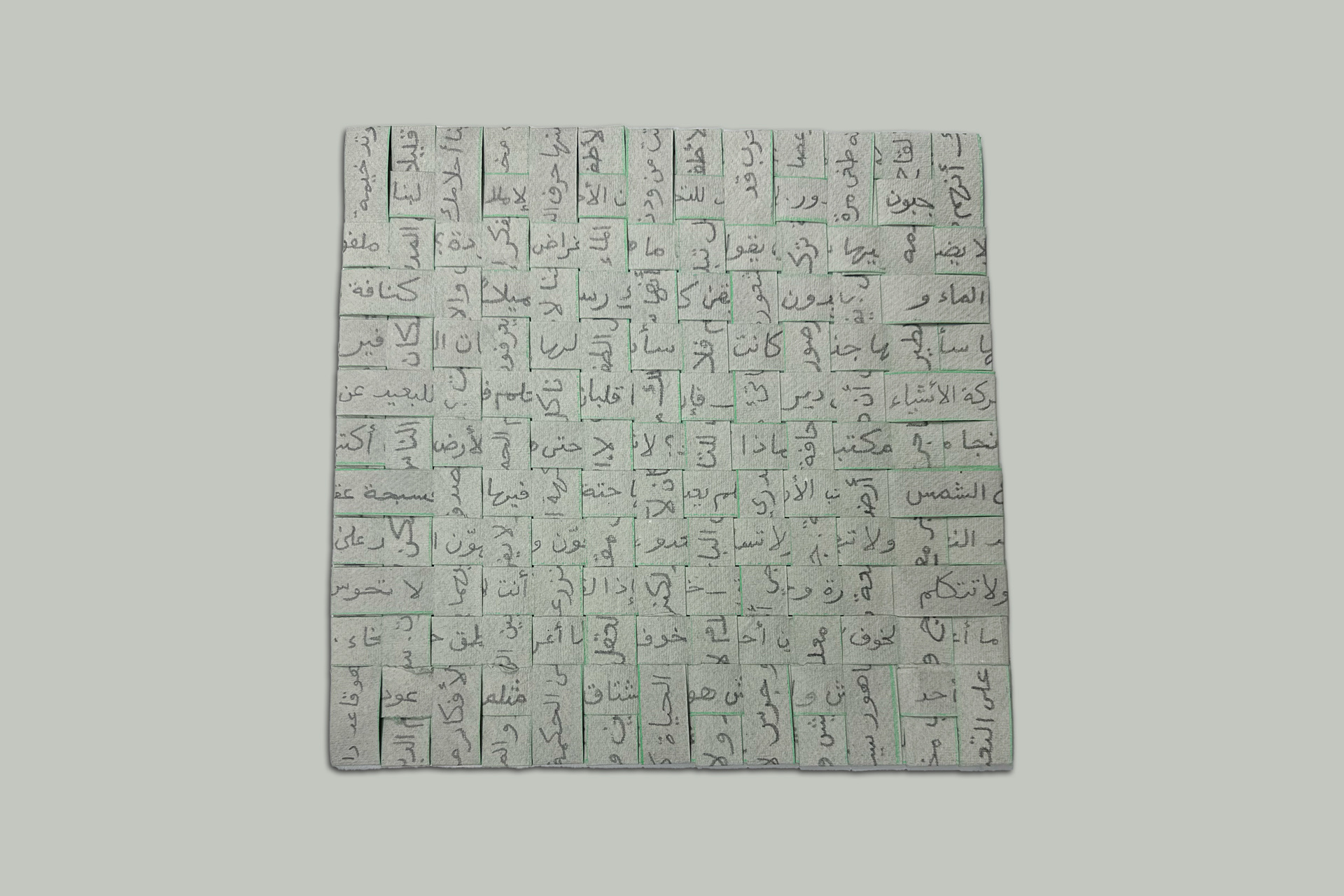 A light grey square of woven strips of rag paper with Arabic handwriting written on each strip and obscured by the weaving. A pea green pencil colour lines appear on the edges of the strips indicating cutting marks