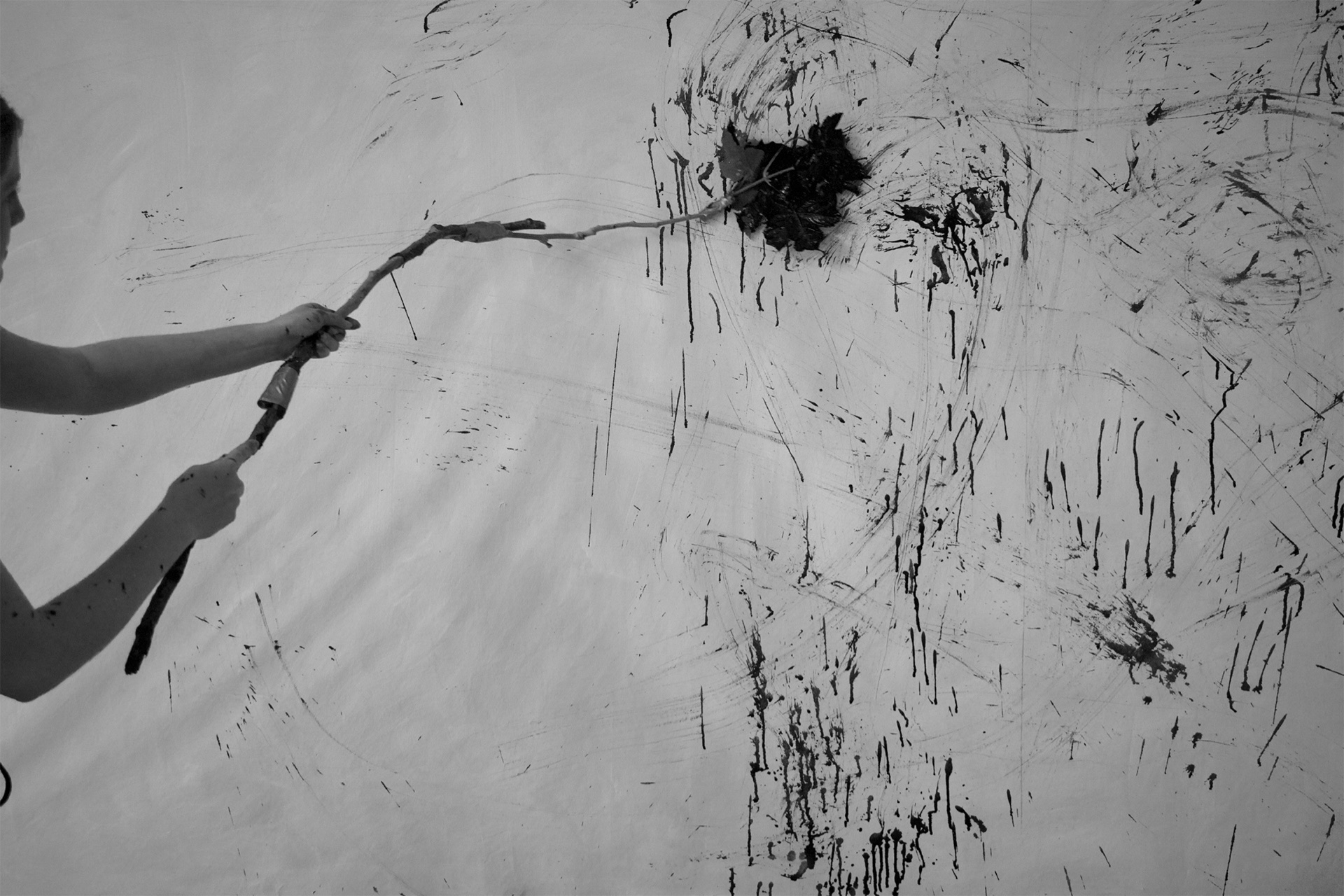 a stick dipped in ink, all in black and white, being dragged along a large canvas.