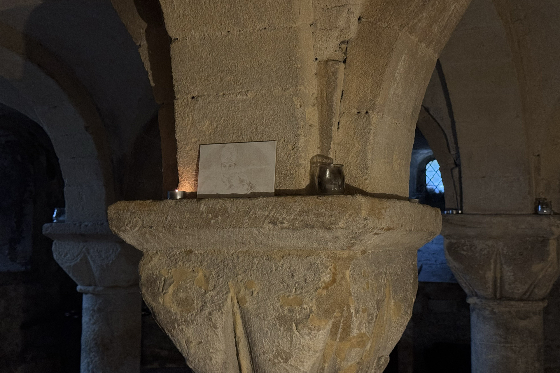Image shows an installation shot from St. Peter’s Crypt in St. Edmund Hall. On the centre pillar a small painting is propped. 