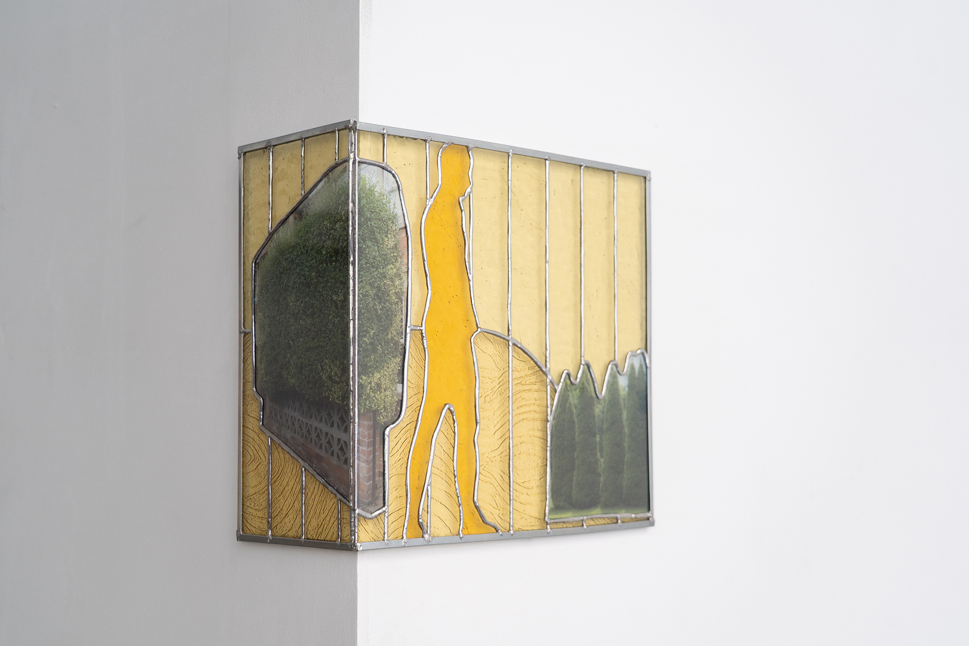 A stained glass piece with a hedge and a man