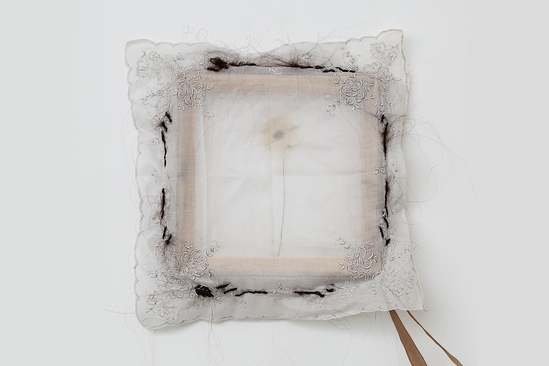 Image of flower behind see through embroidered handkerchief with hair detail