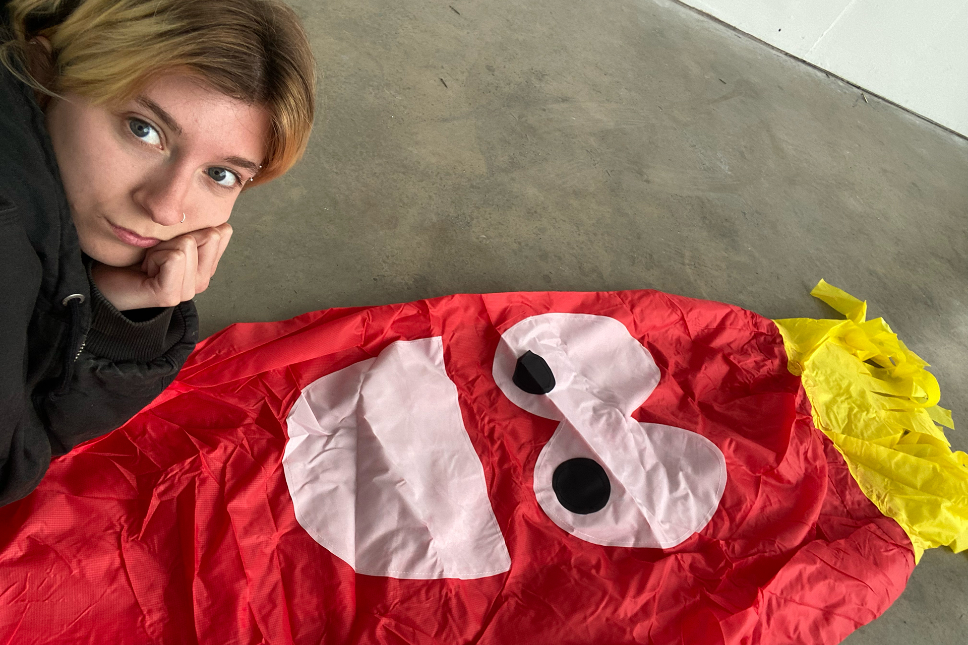 Image of Bliss lying down with a red inflatable man. 