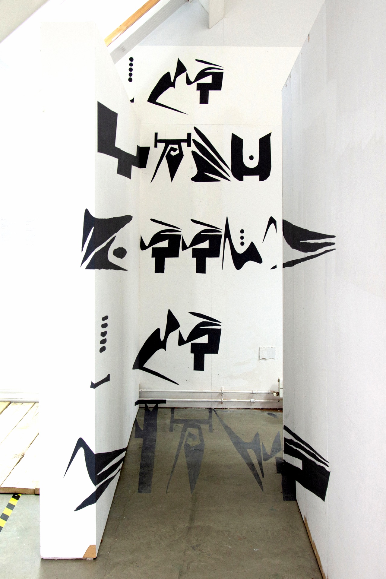 Painted warped letters in artist's own script on wall and floor.