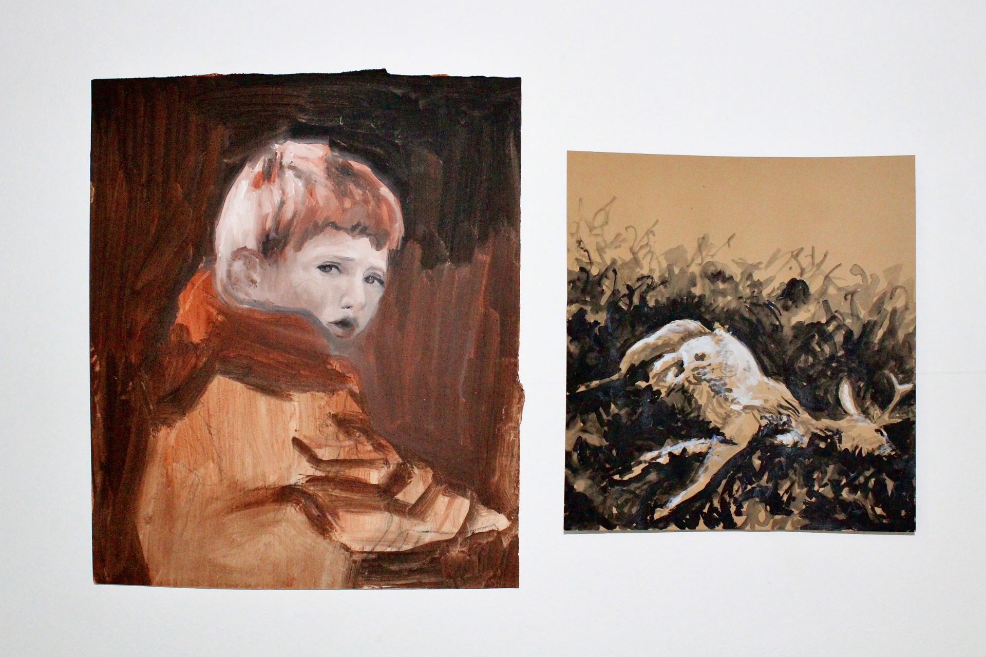 Two paintings next to each other. The one on the left is of a young boy looking at the viewer, the one on the right is of a dead deer.