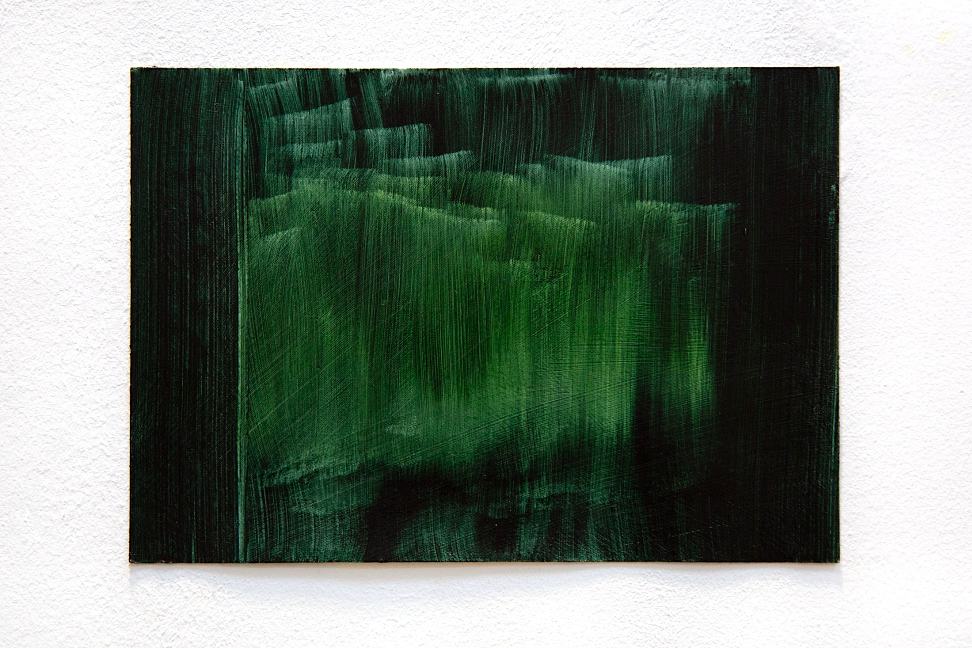 A green painting made with vertical brushstrokes and a yellow hue in the centre.