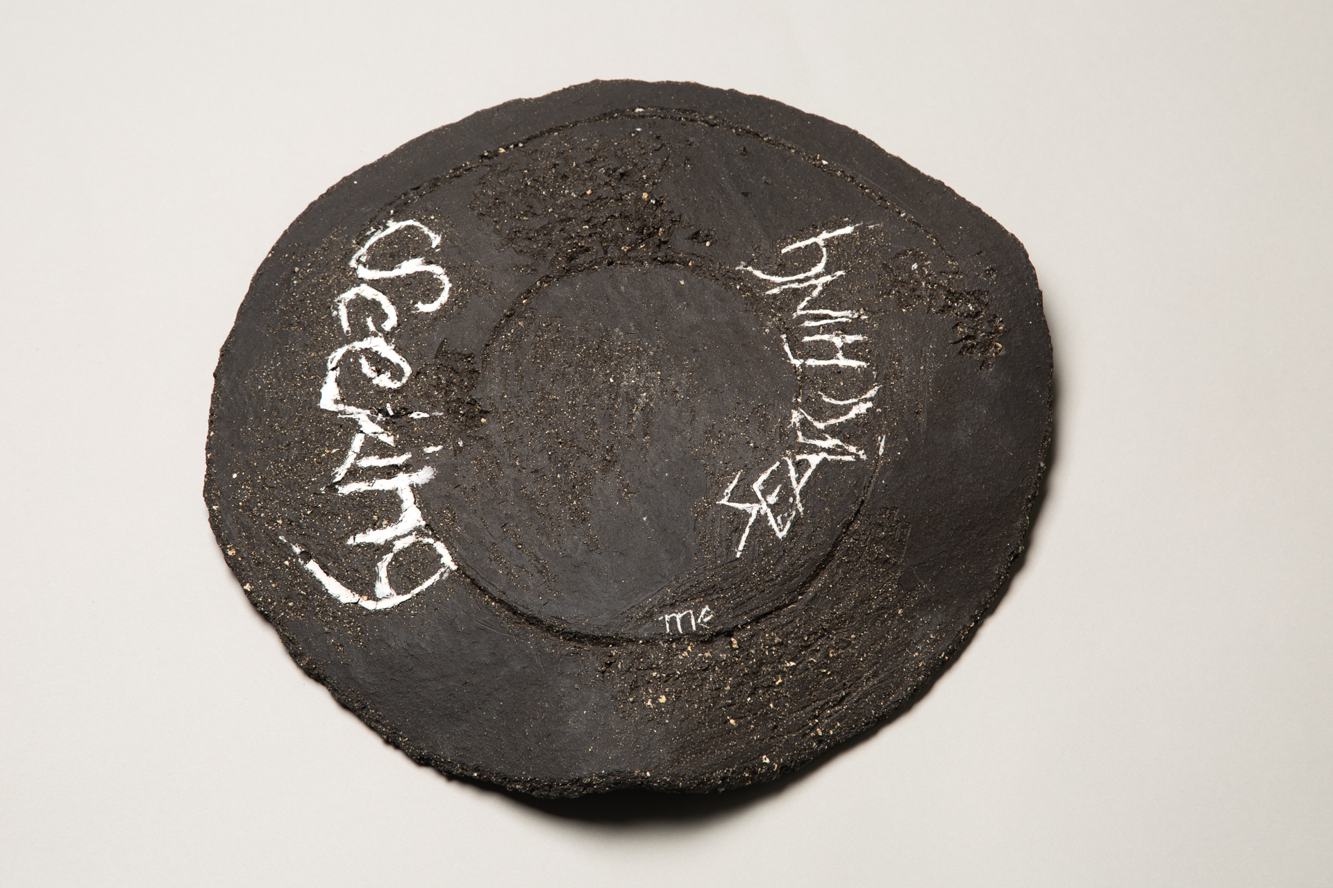 Image of a round disc-like ceramic sculpture made from black and white clay