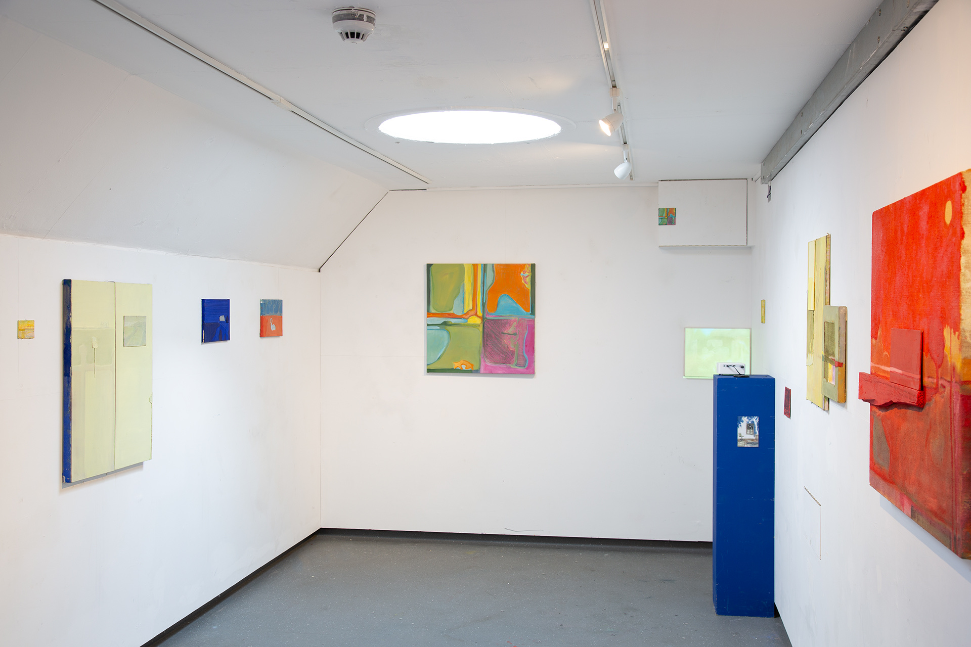 A exhibition room full of variously sized paintings. Colourful 
