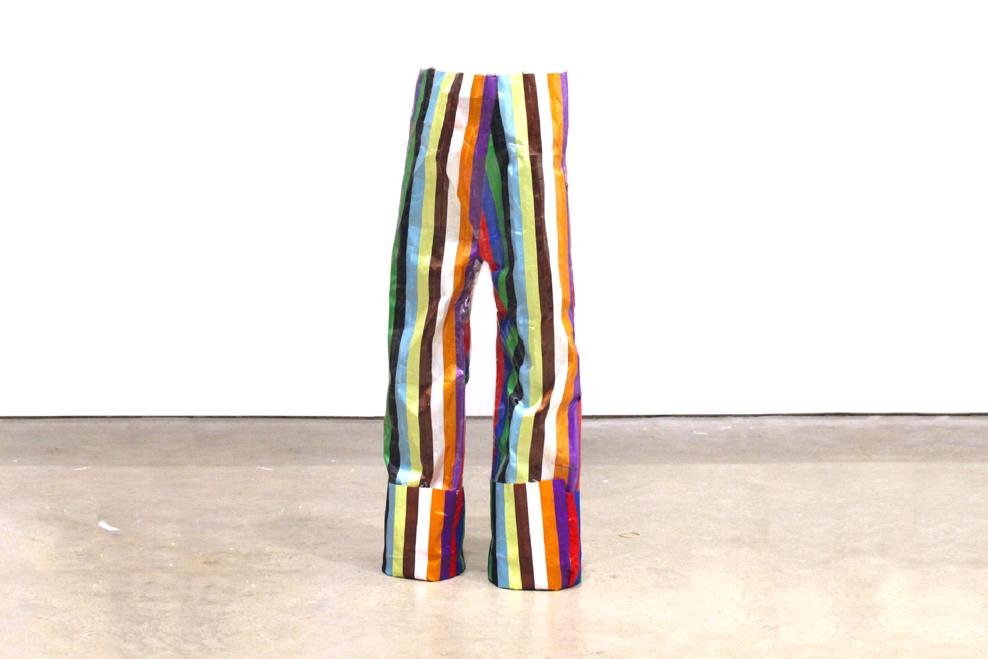 a pair of free-standing striped trousers of vertical ribbons taped together.