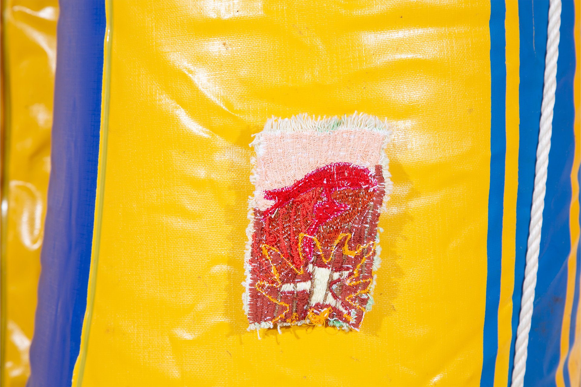 Red and brown embroidered patch with a star shape pattern, pinned to the surface of an inflated yellow dinghy.