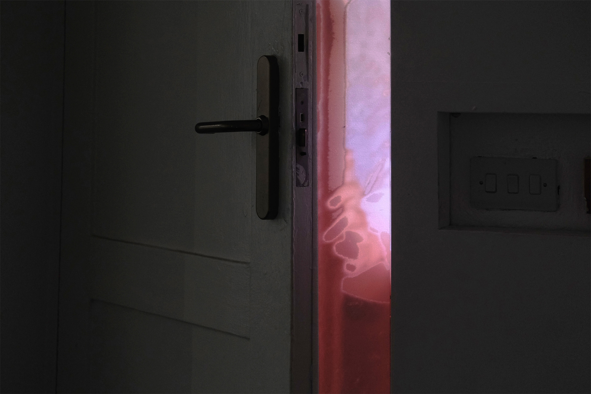 Illuminated wooden slit placed within the gap of an opening door.