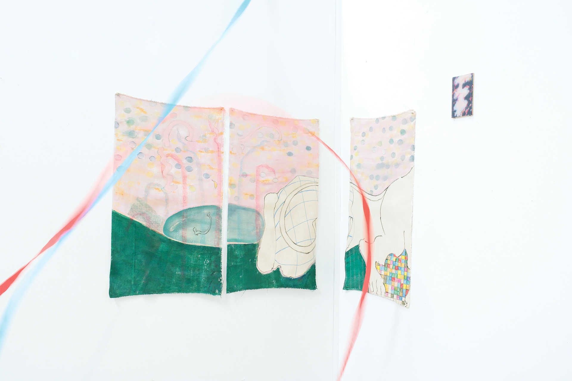Three canvases in pink and green, hung round a corner. The canvases depict the rear end of a heraldic leopard. Blue and red streamers are also in shot.