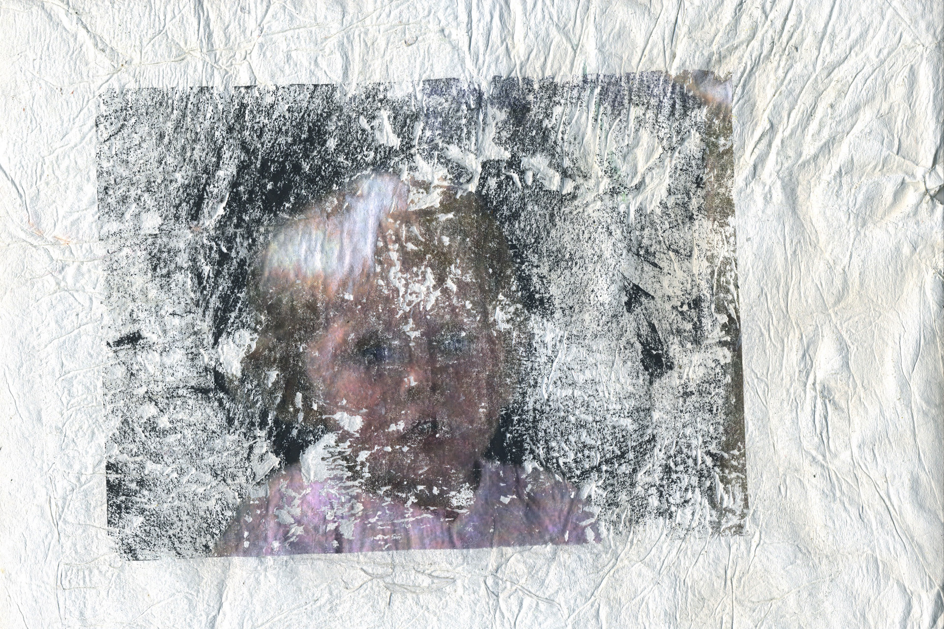 Creased white paper with a worn away image of a child