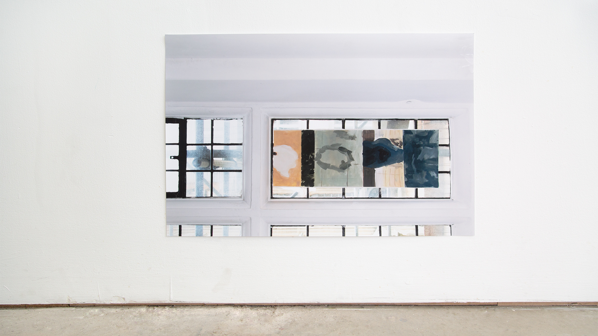 A printed photograph on a wall. The photograph shows a long thin painting attached to a window pane, on its side.