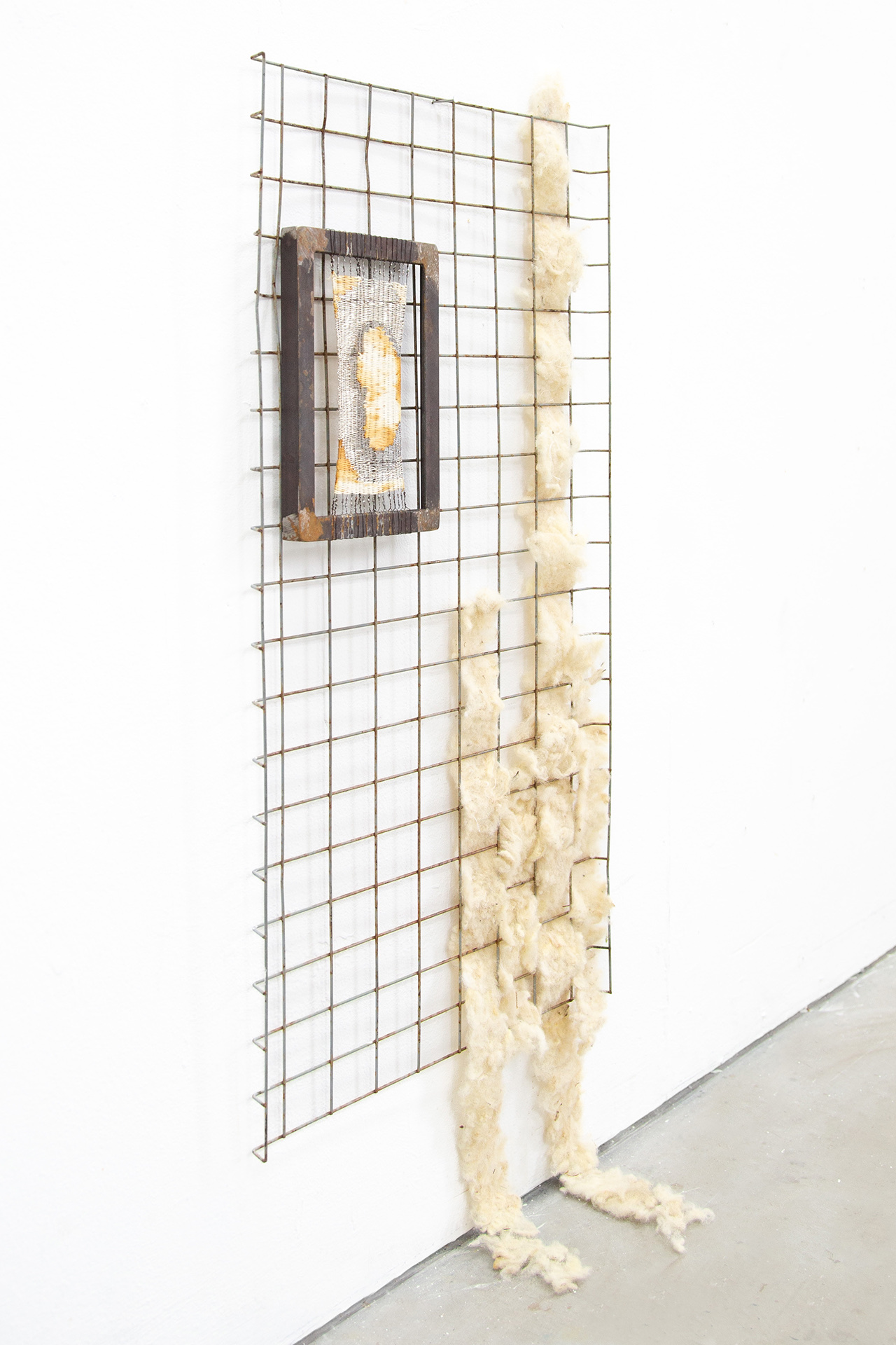 A steel framed weaving in wire and cotton thread that has been treated by rusting agents, sitting against a found metal grating with felted sheep's wool woven through. 