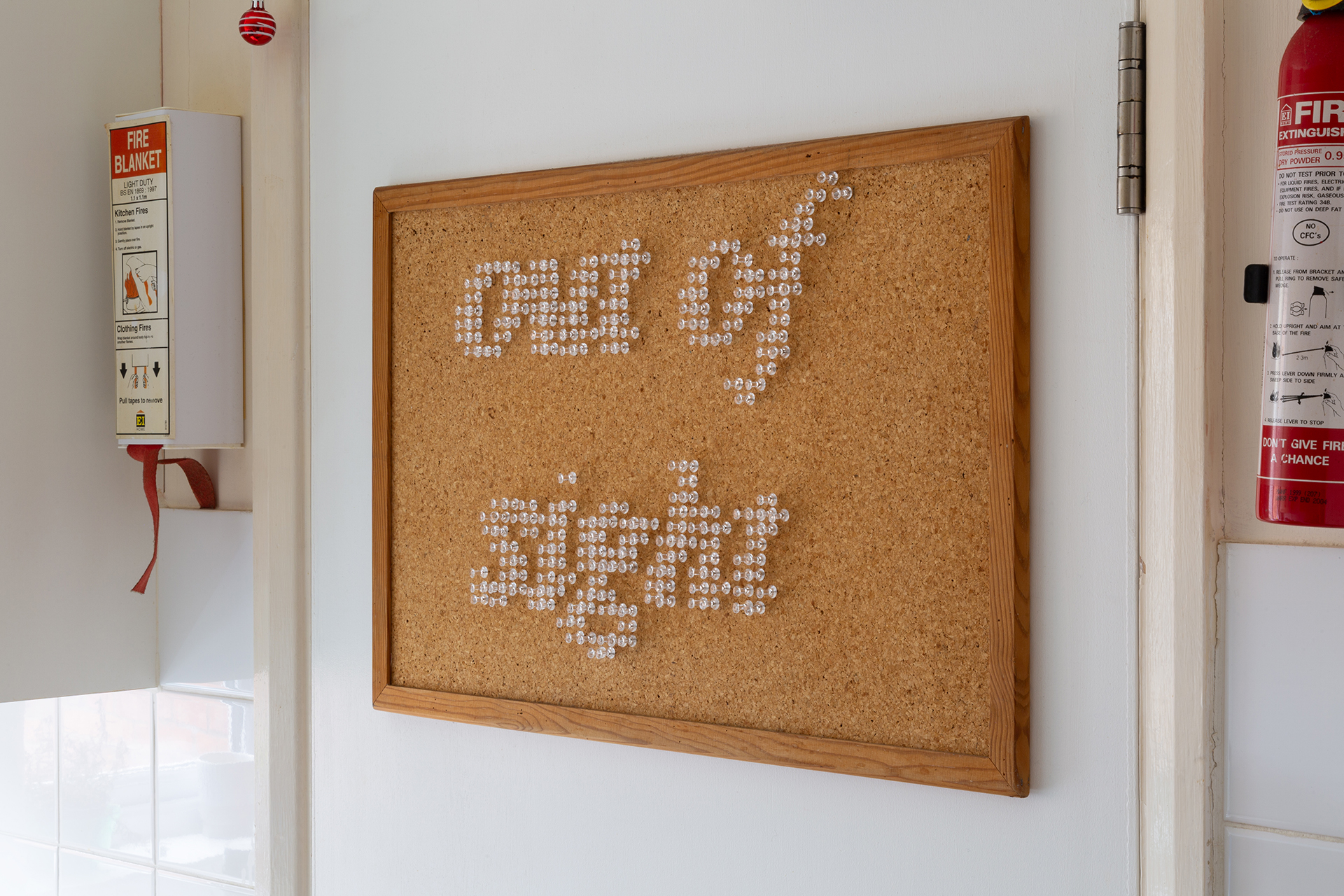 Photgraph depicting a small, cork noticeboard upon which the phrase 