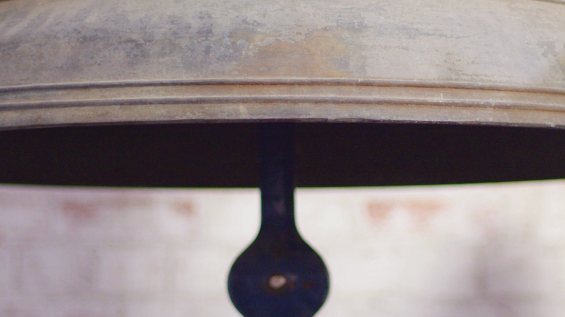 Close-up of the mouth of a bell with a round clapper.