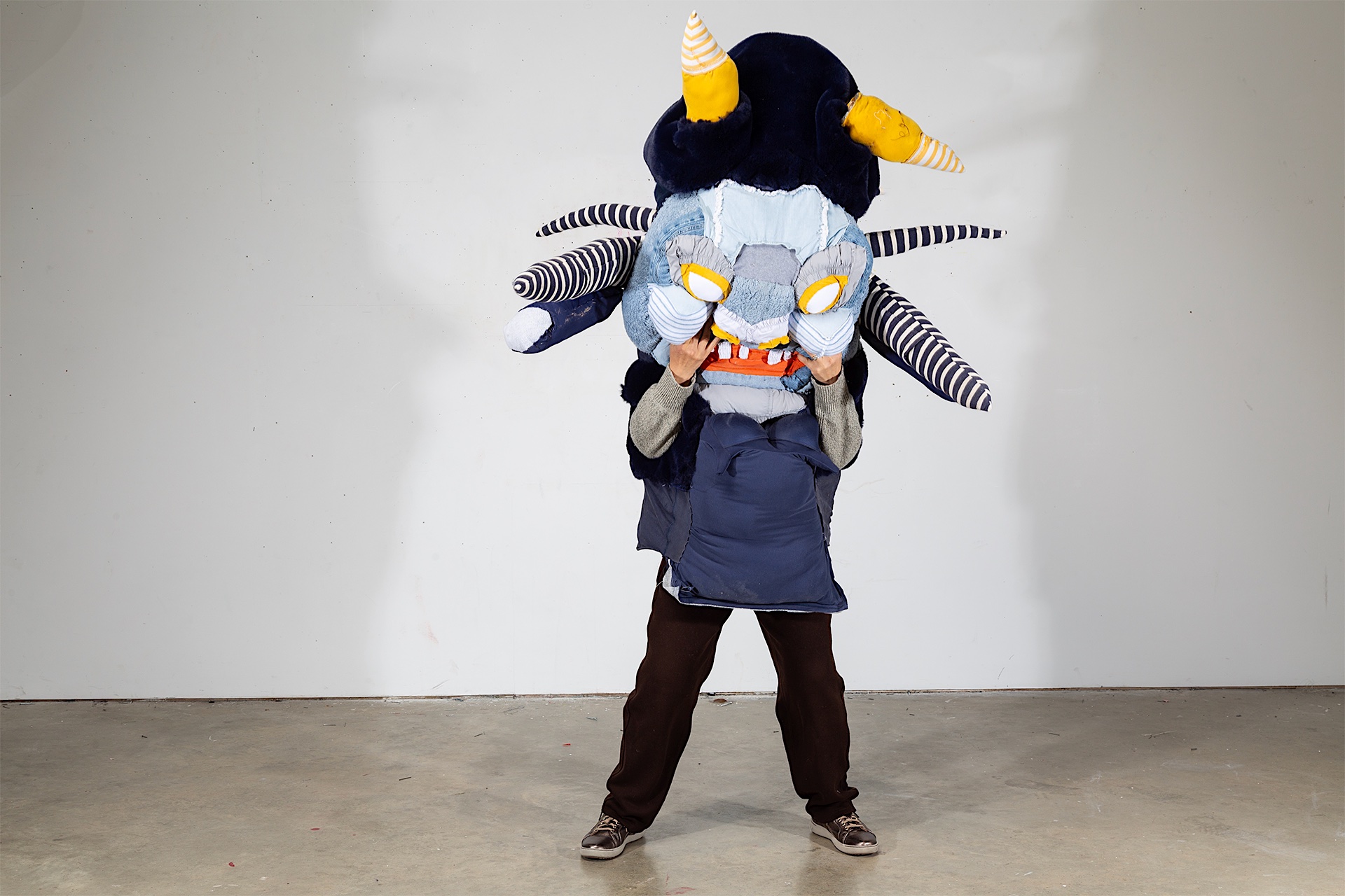 Large costume with striped limbs, yellow horns, and a bulging blue face.