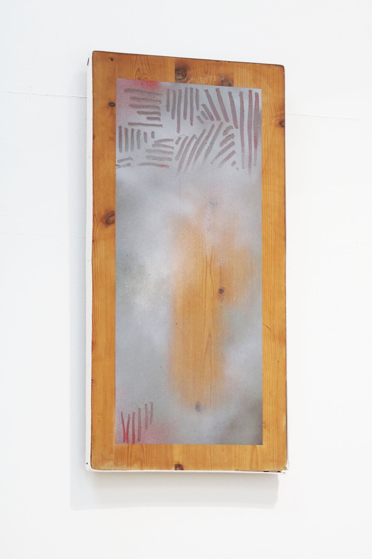 A soft, cloud-like spray-painting on wood floats on the white wall.