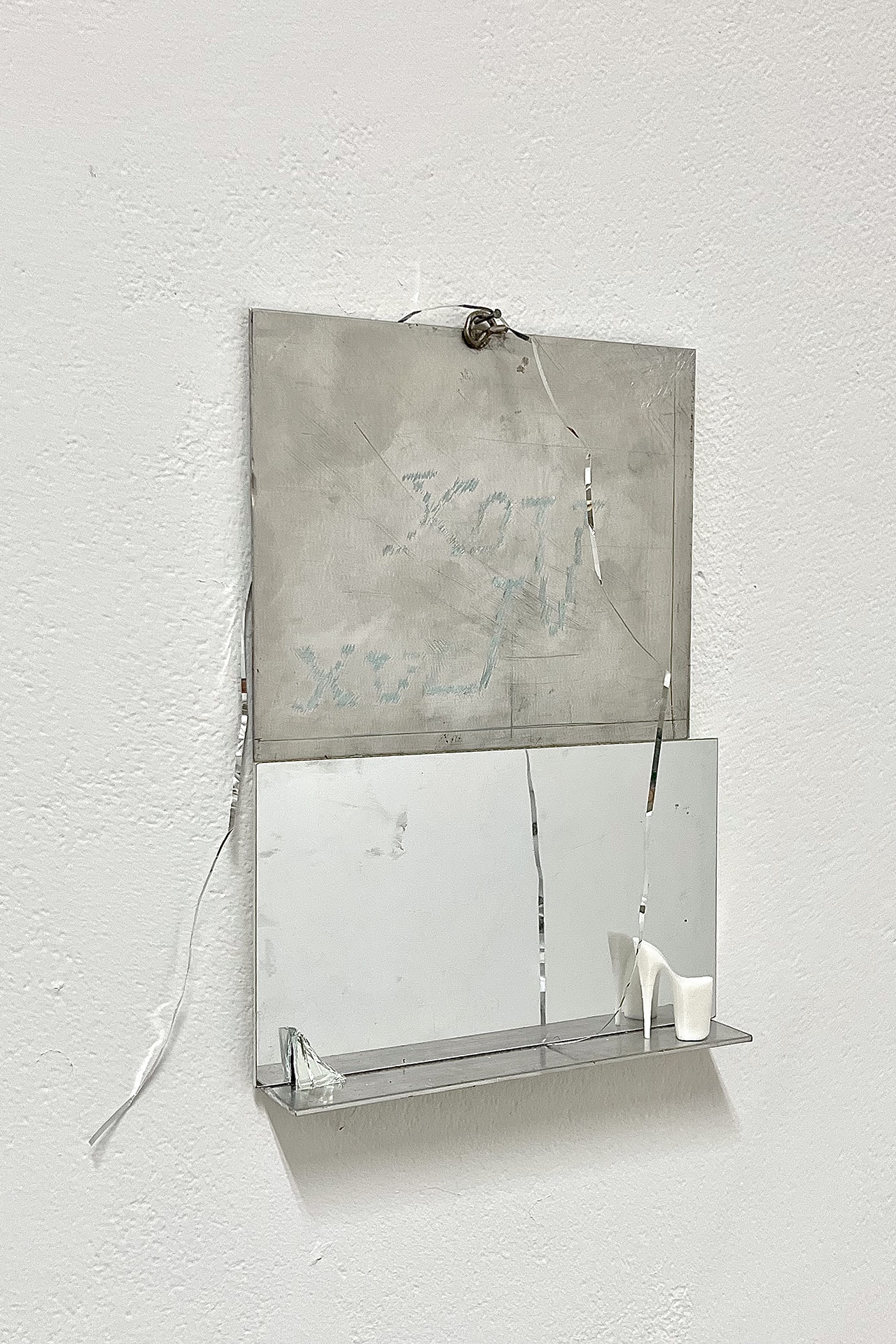 Small sculptural arrangement with high heel and reflective surface reading Vox Lux