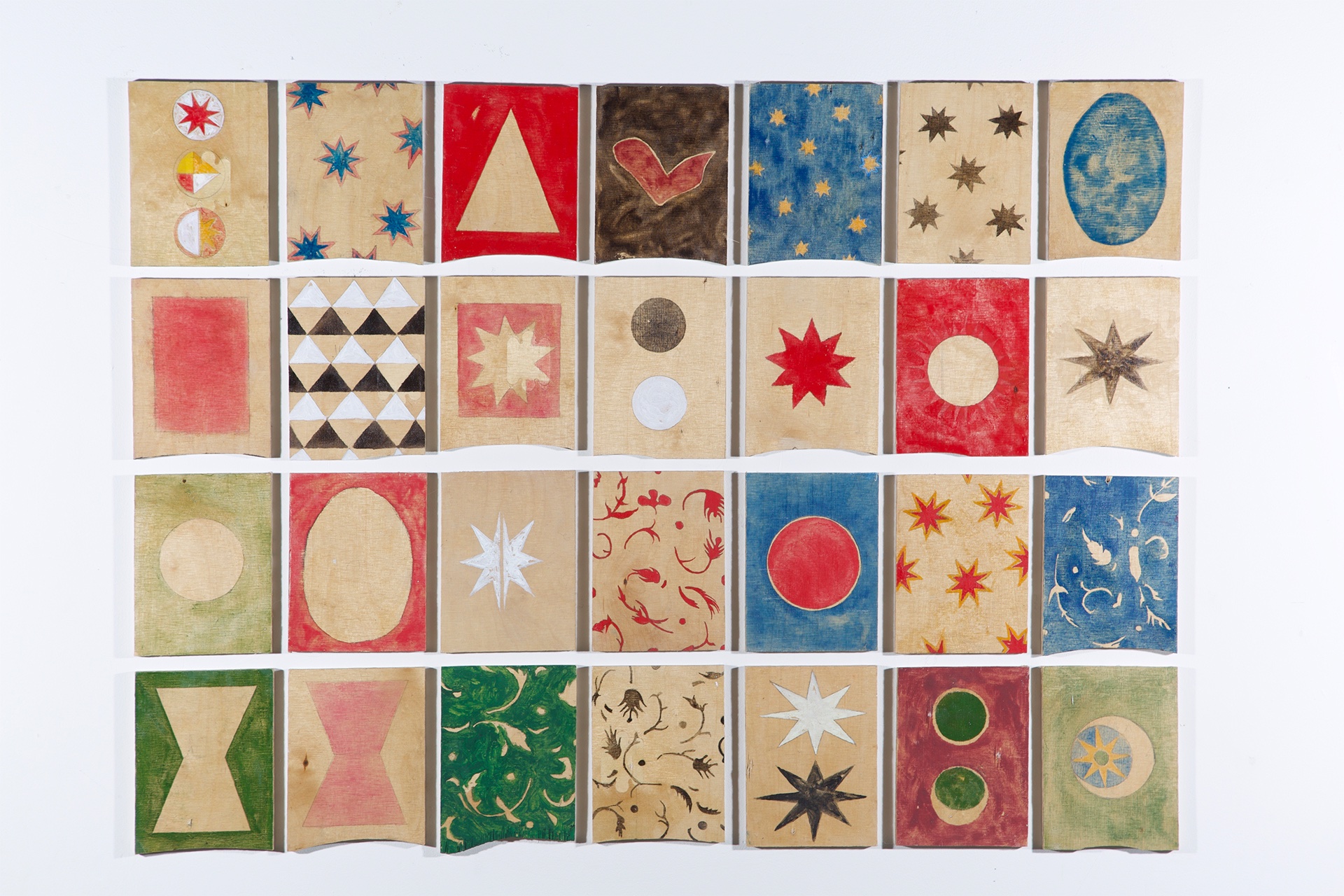 Collection of 28 wood tiles. Painted with various motifs and symbols. Thin layers of paint over exposed wood.