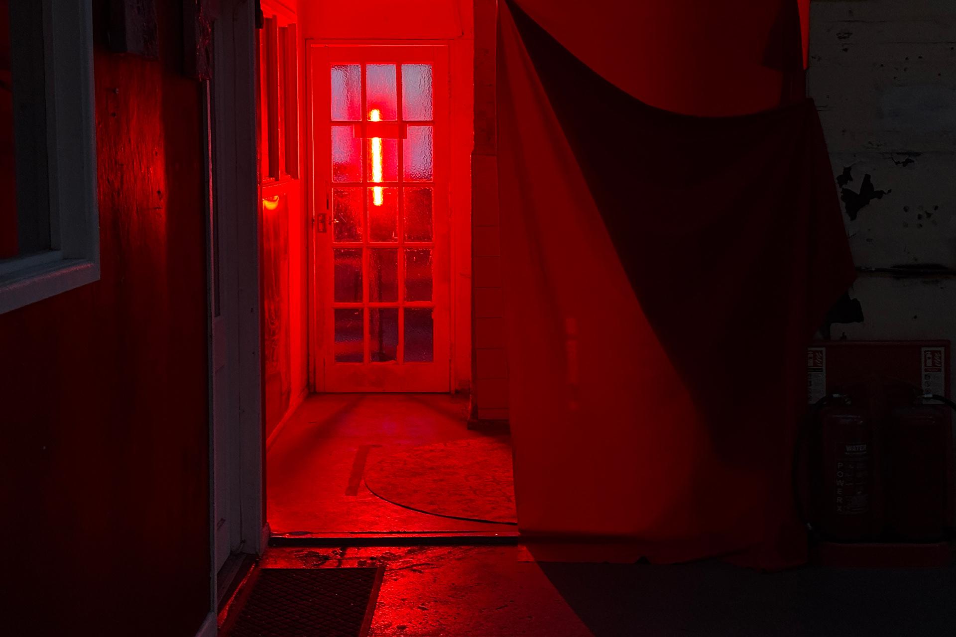 Partially concealed side room, lit in harsh red lighting