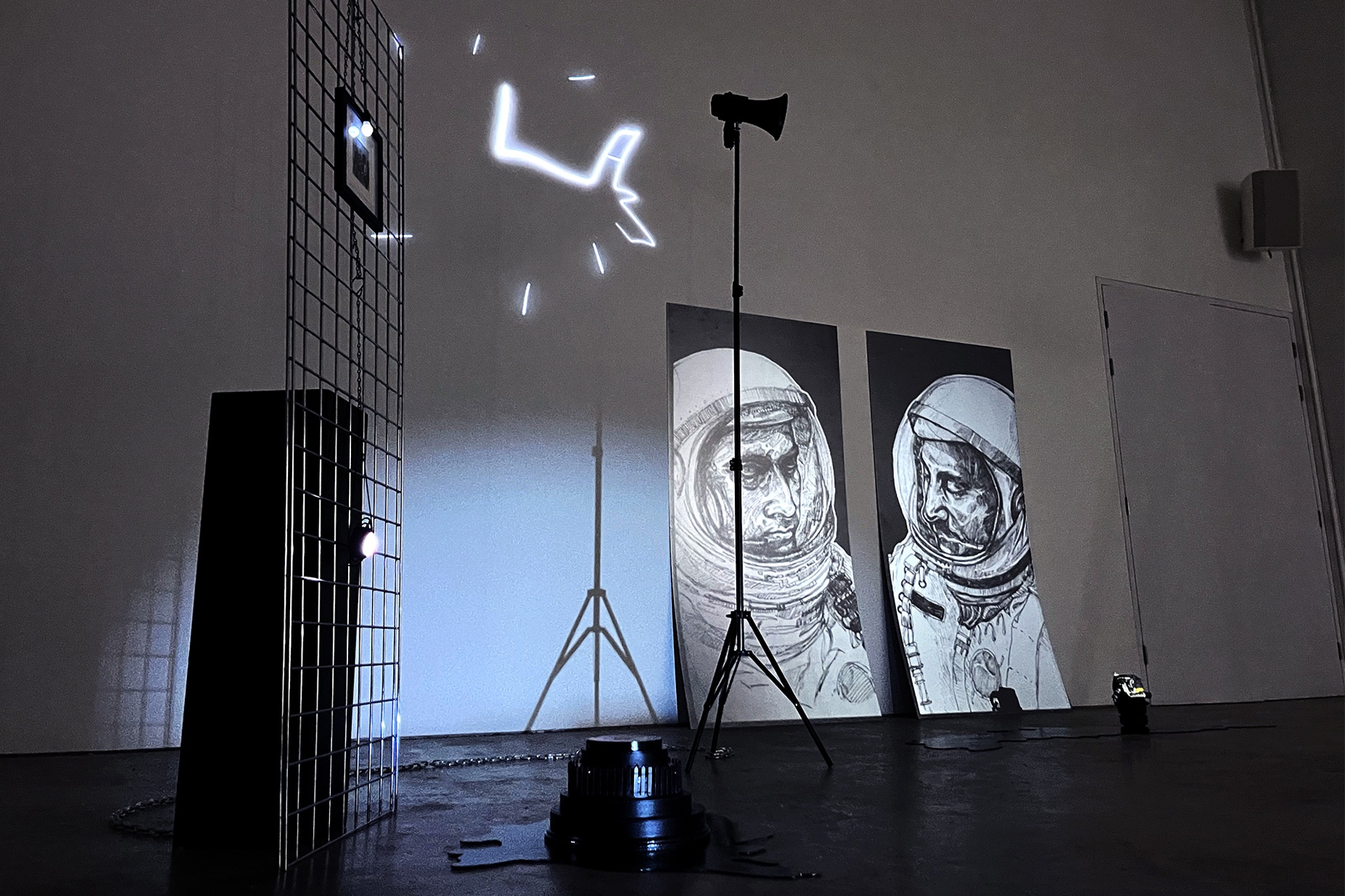 An installation in a dark room featuring a light projection of astronaut drawings.