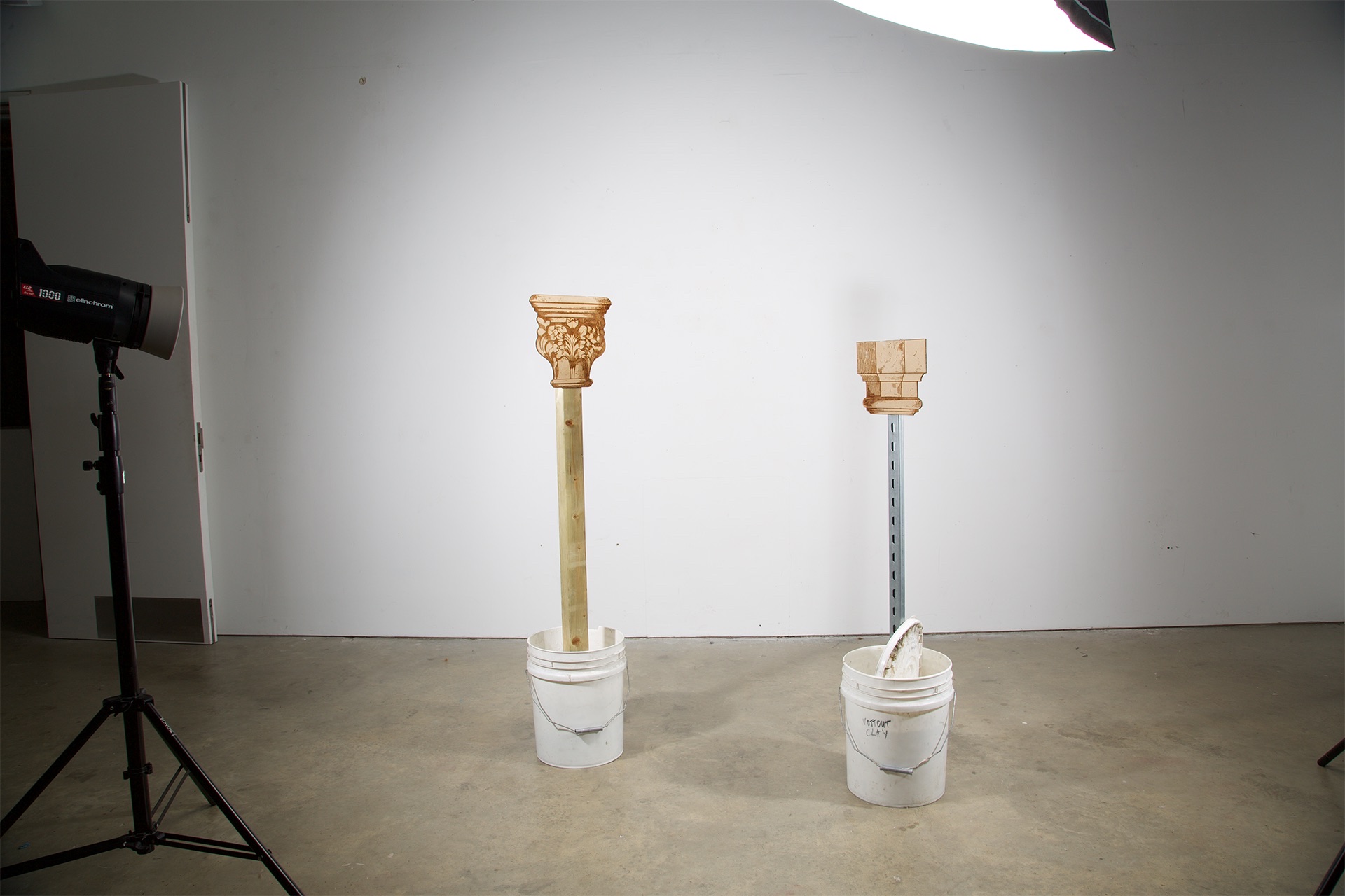 Two mixed media sculptures of gothic columns made from industrial materials, MDF, pine and steel, stemming from buckets.