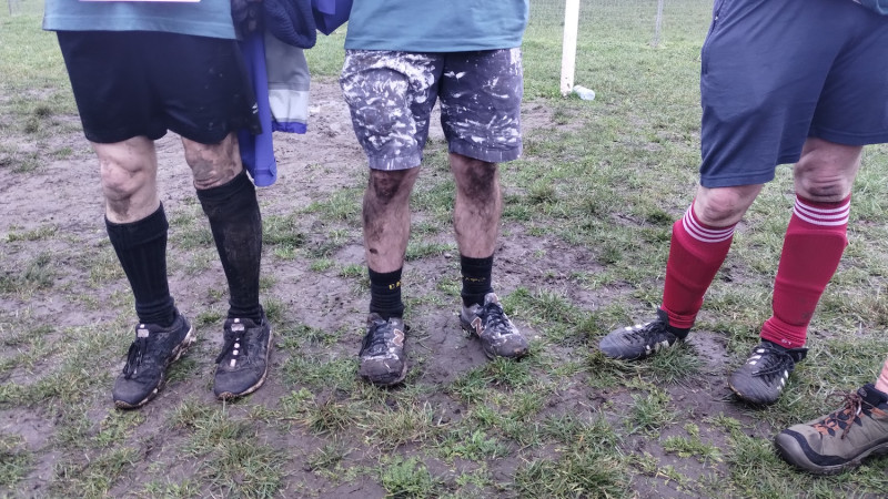 The muddy legs of three players.